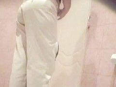 A woman wearing white jeans is pissing in the public toilet